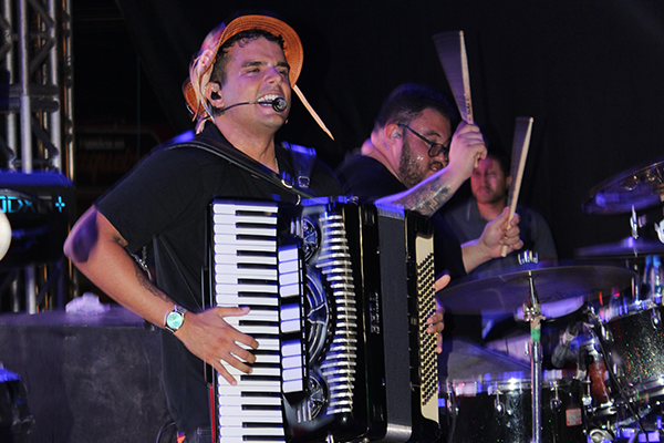 Fotografia do palco do Show da Cultura Católica em Cafarnaum, destacando o público entusiasmado e o artista William Sanfona tocando sua sanfona sob luzes coloridas.