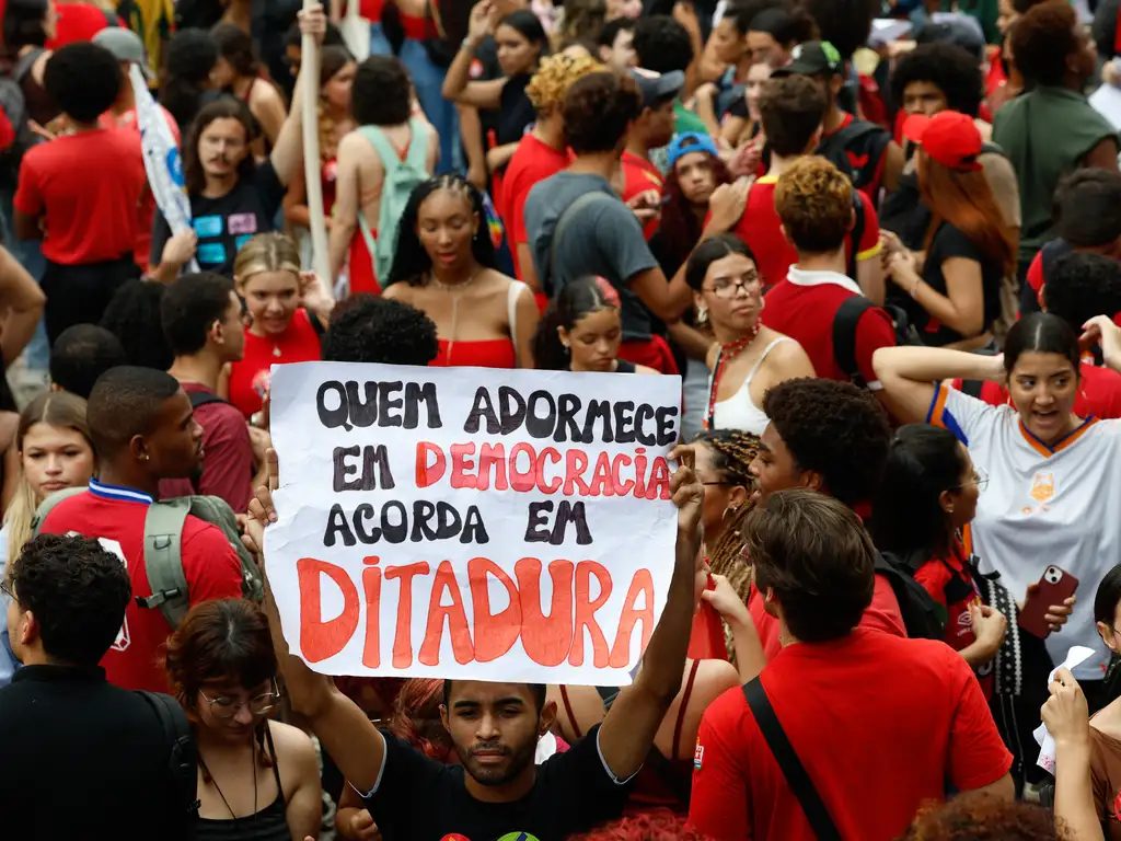 Multidão de manifestantes e estudantes reunidos em passeata segurando bandeiras e faixas durante ato de mobilização política nas ruas.